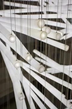 Close up of a composition of white light tubes hanging by small wires Stock Photos
