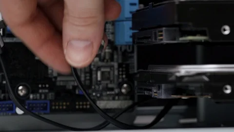 Close-up computer assembly. Male service worker connects SATA cables to hard 库存影片 105422609