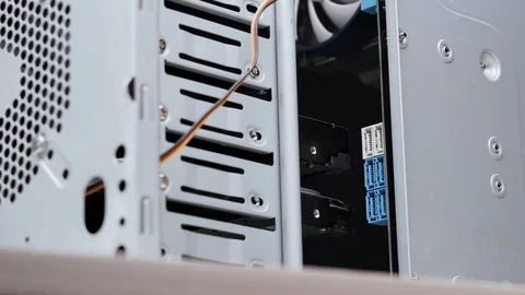 Close-up computer assembly. A man connects sata cables to the motherboard inside 库存影片 105422556