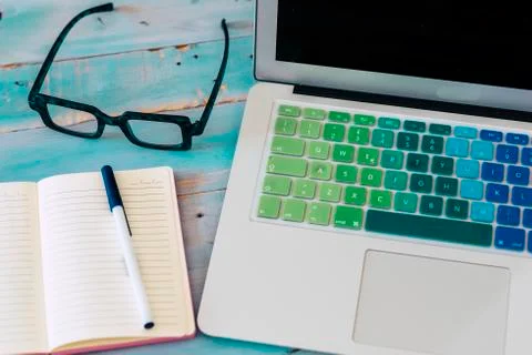 Close up of computer with glasses and notebook with pen on the table with blu 写真素材