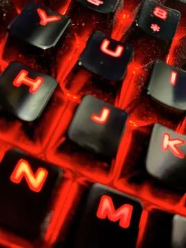 Close up of a computer keyboard with red glowing letters in it. Foto stock