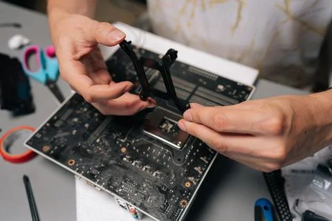 Close-up of computer technician mounting CPU cooler bracket on motherboard Stock Photos