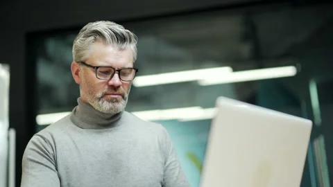 Close up of concentrated mature gray-haired bearded businessman in glasses typ Stock Footage 232579528