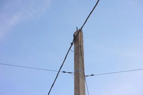 Close-up of a concrete post with optical cable and fixing wires on it against Stock Photos