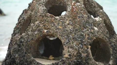 Close up of concrete reef ball burials with holes for fish on the beach. Protect Stock Footage 270236190
