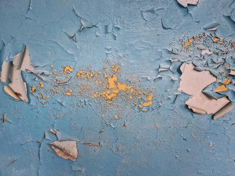 Close-up concrete wall with peeling blue paint revealing patches of yellow .. Stock Photos