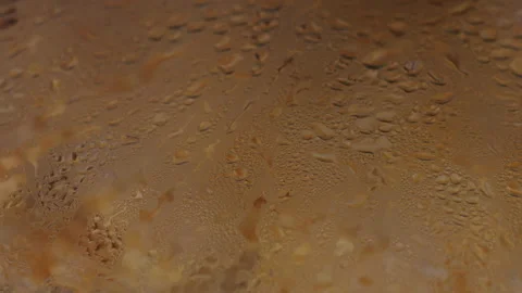 Close-up of condensation droplets on a cold glass surface with warm golden light 動画素材 342385955