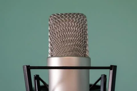 Close-up of a condenser studio microphone with a shock absorber on a blue bac Stock Photos