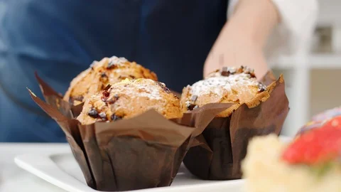 Close up confectioner hands sprinkle chocolate chips to muffin. 4k Dragon RED Vidéo 124923974
