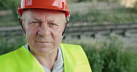 Close confident look into camera of senior railroader in uniform at railway Video stock 135571553
