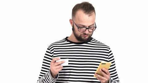 Close-up of a confused young man with beard using his cellphone. He’s holding Stock Footage 120978306