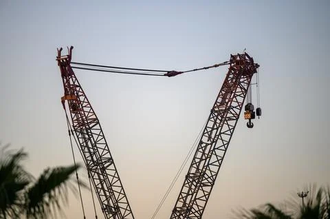 Close-up of a construction crane with intersecting booms at dusk Stock Photos