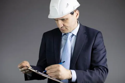 Close up construction engineer in hard hat making notes on clipboard Stock Photos