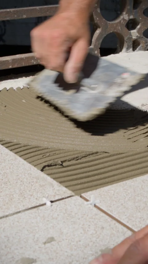 Close up of construction notched trowel applying adhesive mortar on floor. Stock Footage 328411808
