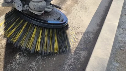 Close-up of a construction road sweeper truck brush rotating and spraying water Vídeos de archivo 330799564
