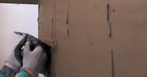 Close-up of construction tool, man smooths adhesive mortar on wall in bathroom Stock Footage 130366418