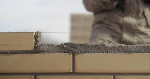 Close-up of construction work, bricklayer puts another yellow brick into mortar Stock Footage 130780222
