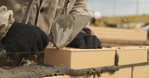 Close-up of construction work, bricklayer puts another yellow brick into mortar Stock Footage 144164643
