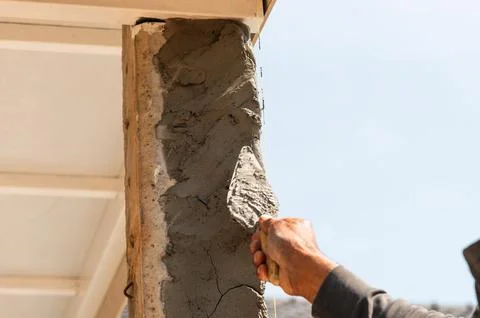 Close-up of construction worker applying cement to column in urban environm.. Stock Photos