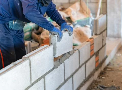 Close up of construction worker building a concrete block wall with mortar Stock Photos