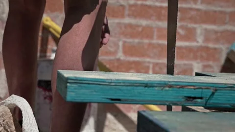 Close-up of a construction worker cutting painted timber with a hand saw on a Stock Footage 337445422