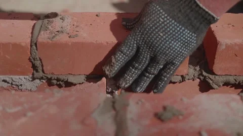 Close-up of a construction worker gloved hands, laying red bricks Vídeos de archivo 335752734