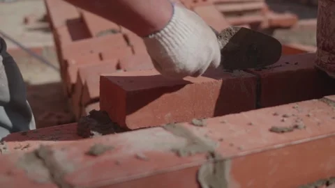 Close-up of a construction worker gloved hands, laying red bricks Video stock 335752868