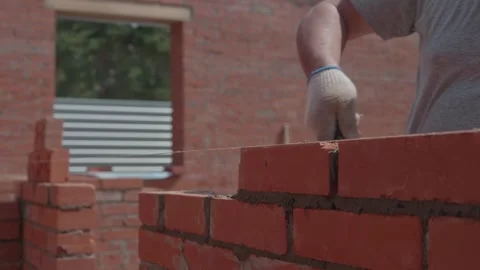 Close-up of a construction worker gloved hands, laying red bricks Stock Footage 336272149