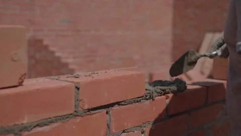 Close-up of a construction worker gloved hands, laying red bricks Video stock 336272173