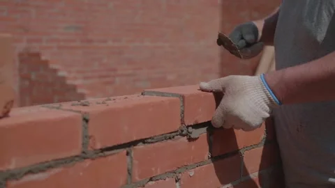Close-up of a construction worker gloved hands, laying red bricks Stock Footage 336739092