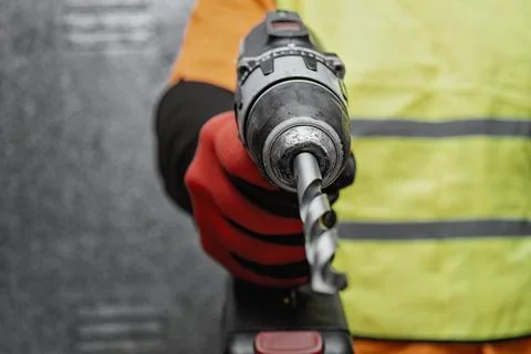 Close up of a construction worker hand holding a cordless drill with drill .. Stock Photos