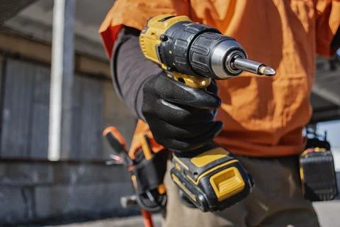 Close up of construction worker holding cordless drill at building site. Co.. Stock Photos