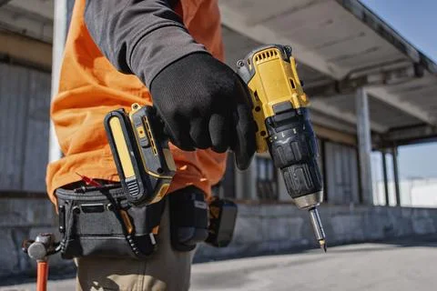 Close up of construction worker holding cordless drill at building site. Co.. Stock Photos