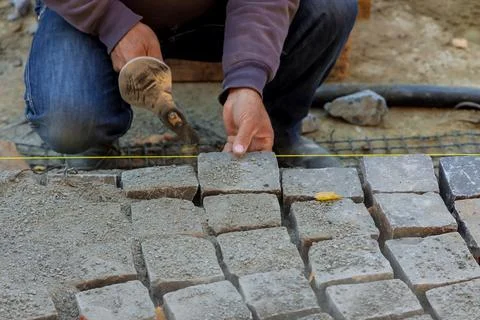Close-up of construction worker installing and laying stones on road sidewalk Stock Photos