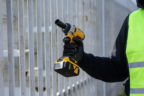 Close-up of a construction worker using a cordless impact drill to attach a m Stock Photos