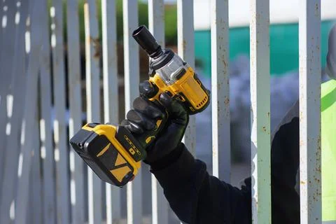 Close-up of a construction worker using a cordless impact drill to attach a m Stock Photos