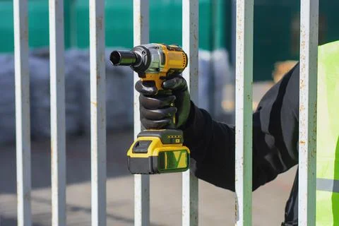Close-up of a construction worker using a cordless impact drill to attach a m Stock Photos
