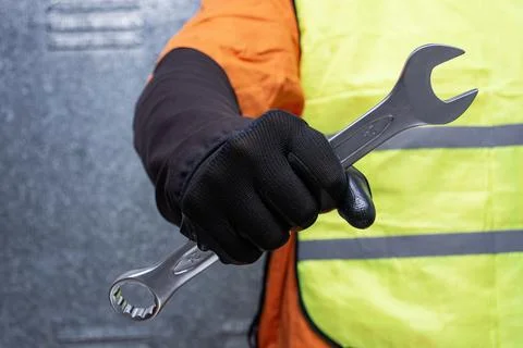 Close-up of a construction worker wearing safety gloves and reflective vest.. Stock Photos