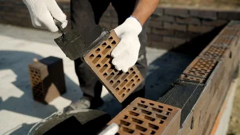A close-up of construction workers carefully laying bricks for a new wall, hi Stock Photos