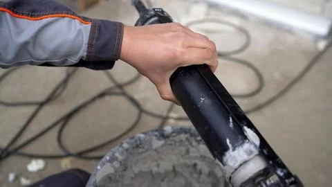 Close up of a construction worker's hand mixing cement with an electric tool. 스톡 사진