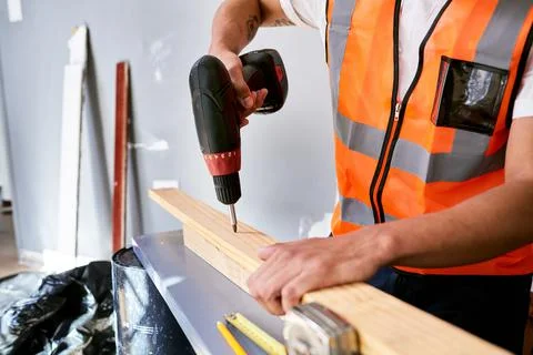 Close up of a construction worker's hands preparing to drill into wooden planks Stock Photos