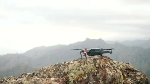 Close up of a consumer drone launching and taking flight off from a rough rock Stock-Footage 111455560