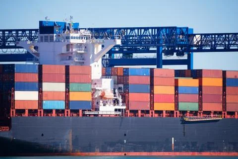 Close up of a container ship full loaded under the crane bridge Stock Photos