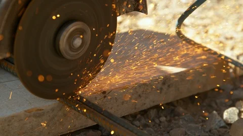 CLOSE UP: Contractor cuts into two rusty metal rods with an angle grinder. Stock Footage 120064509