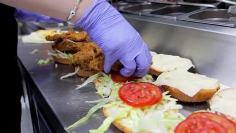Close-Up of Cook Assembling Burgers with Fried Meat and Vegetables Stock Footage 288576094