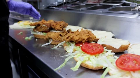 Close-Up of Cook Assembling Burgers with Fried Meat and Vegetables Stock Footage 288576107