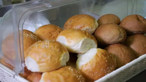 Close-up of a cook in a bakery putting freshly baked buns in a bread box. Buffet Stock Footage 318658999
