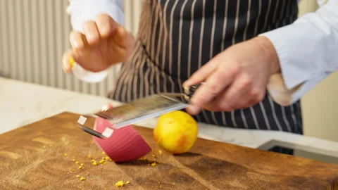 Close-up, a cook clumsily grates orange peel to prepare a sweet dish. Stock Footage 309294433