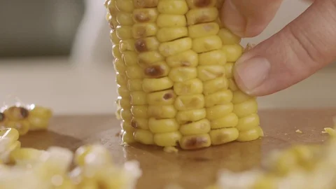 Close-up of cook cutting corn-baked corn on kitchen table with sharp knife Stock Footage 114544710