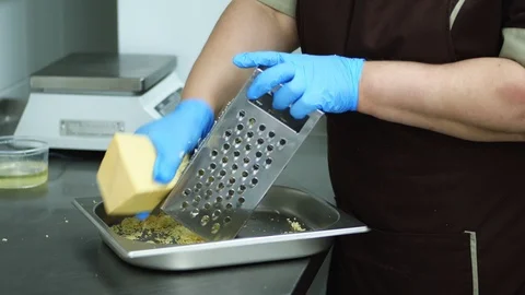 Close-up, a cook in gloves rubs the cheese on a grater, makes the preparation Stock Footage 103577134